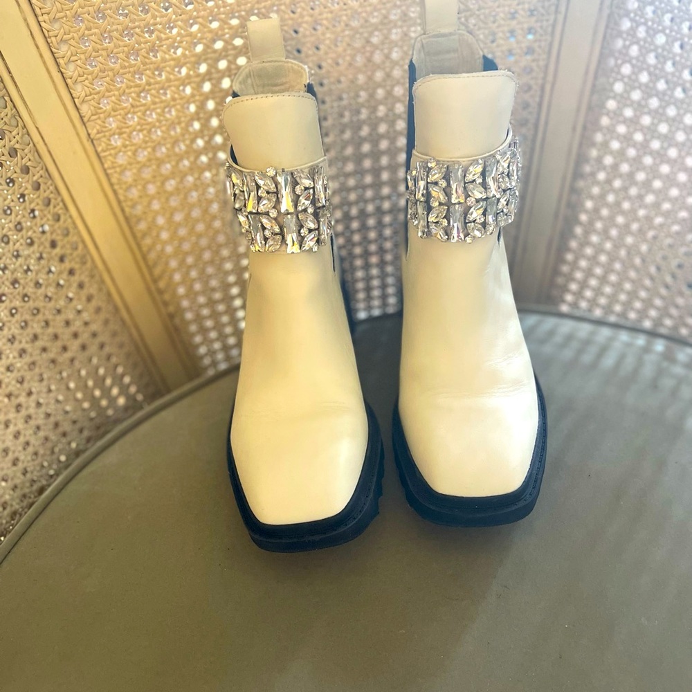 Soft white leather booties with black soles and jeweled ankle straps.